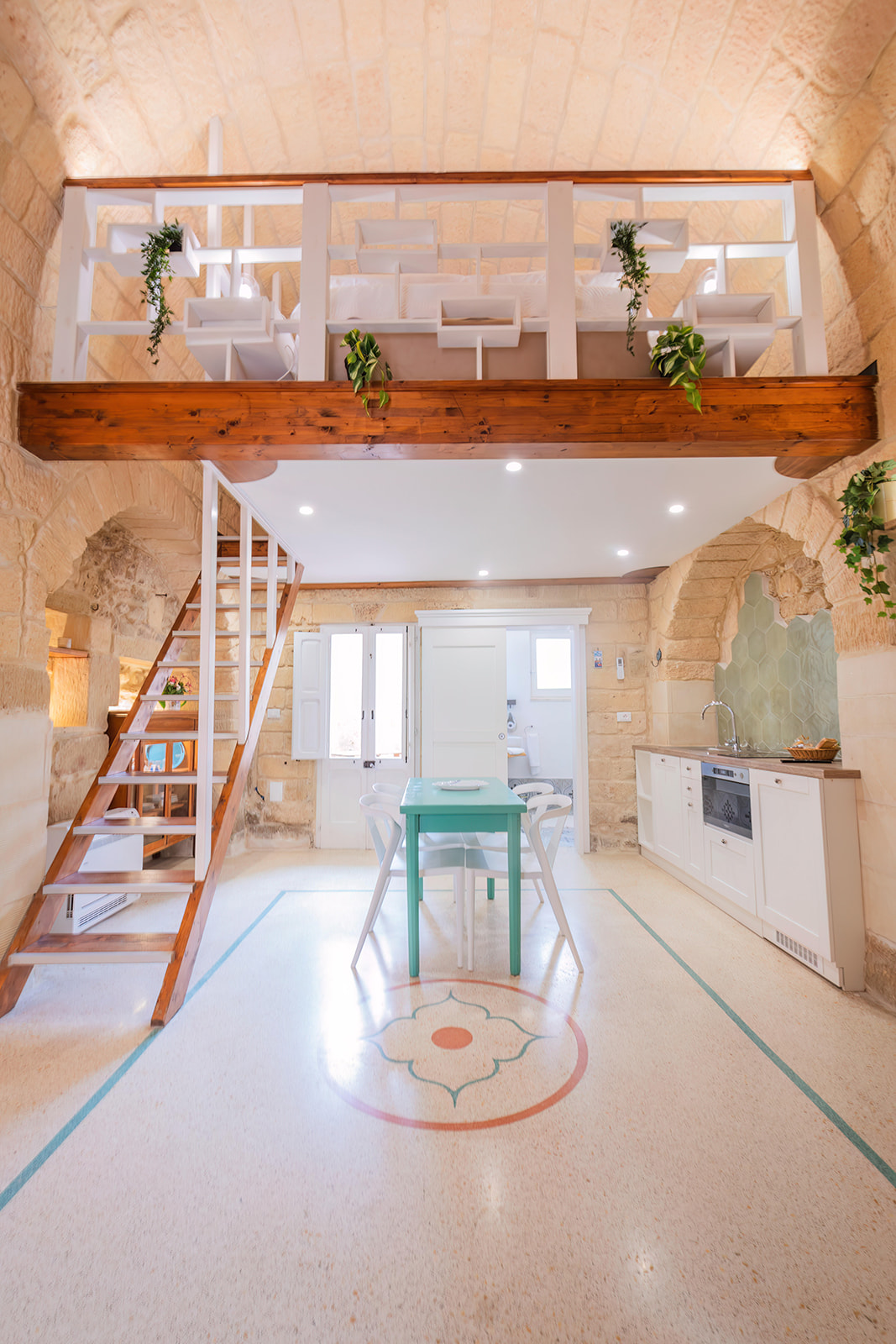 Vista frontale del soggiorno con scala, soppalco letto e cucina