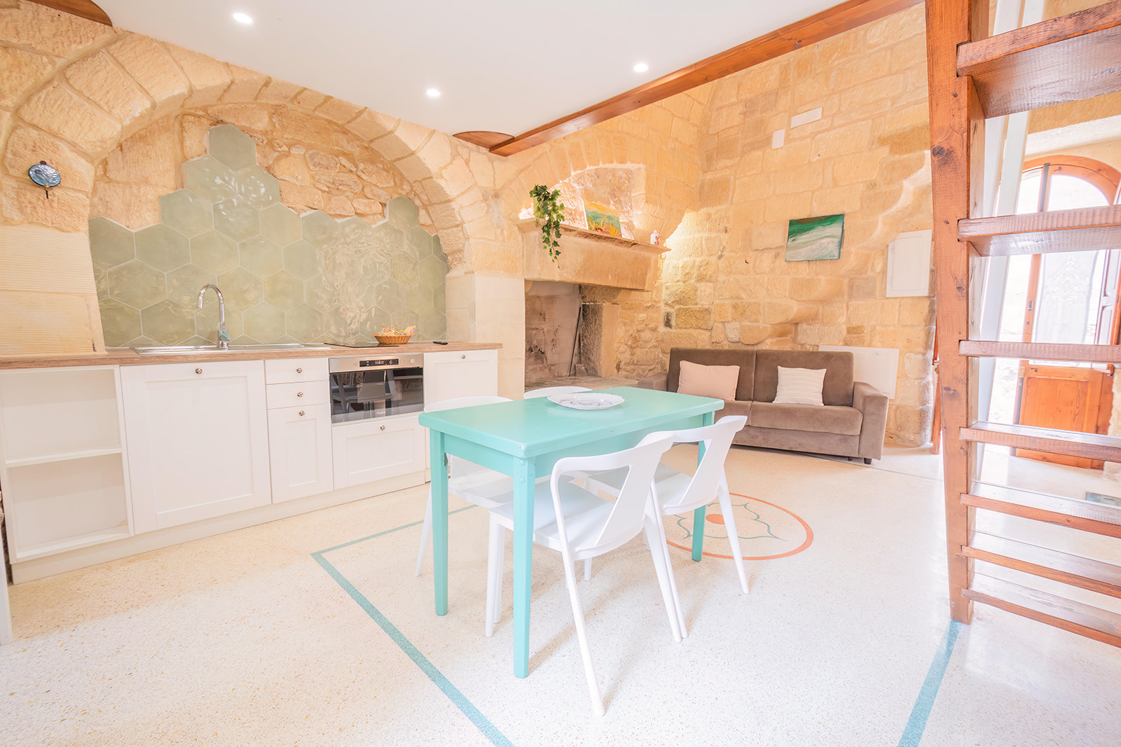 Cucina attrezzata con backsplash esagonale verde salvia e camino in pietra