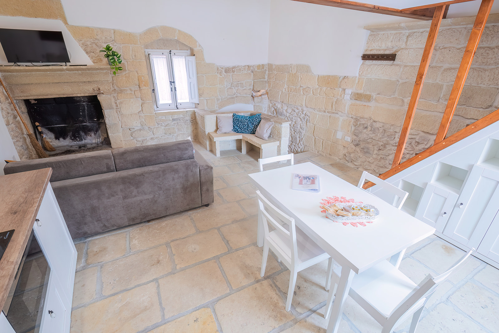 Zona pranzo con camino antico in pietra e panchetta in muratura nella nicchia