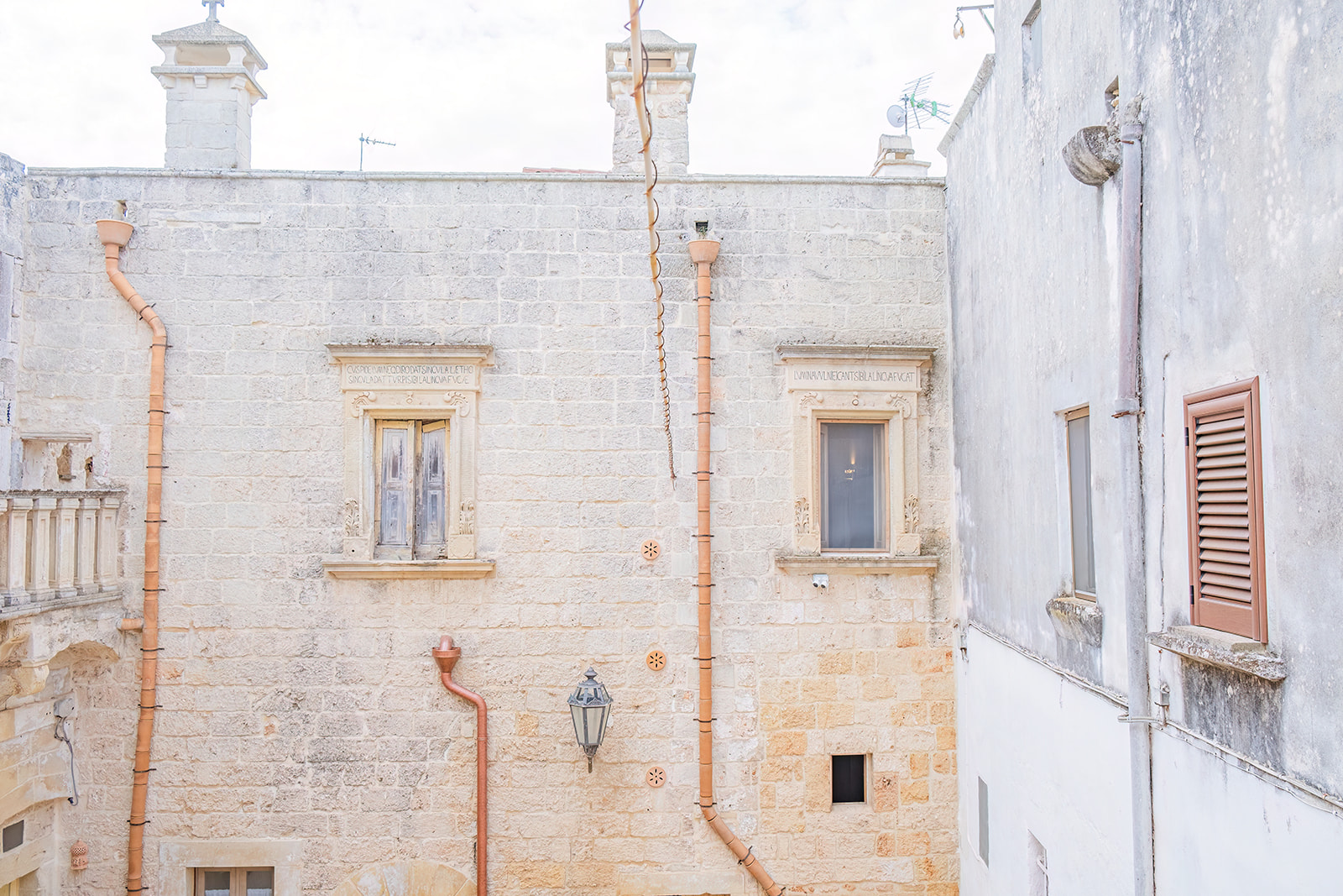 Facciata storica della corte con due finestre in pietra leccese e iscrizioni latine scolpite
