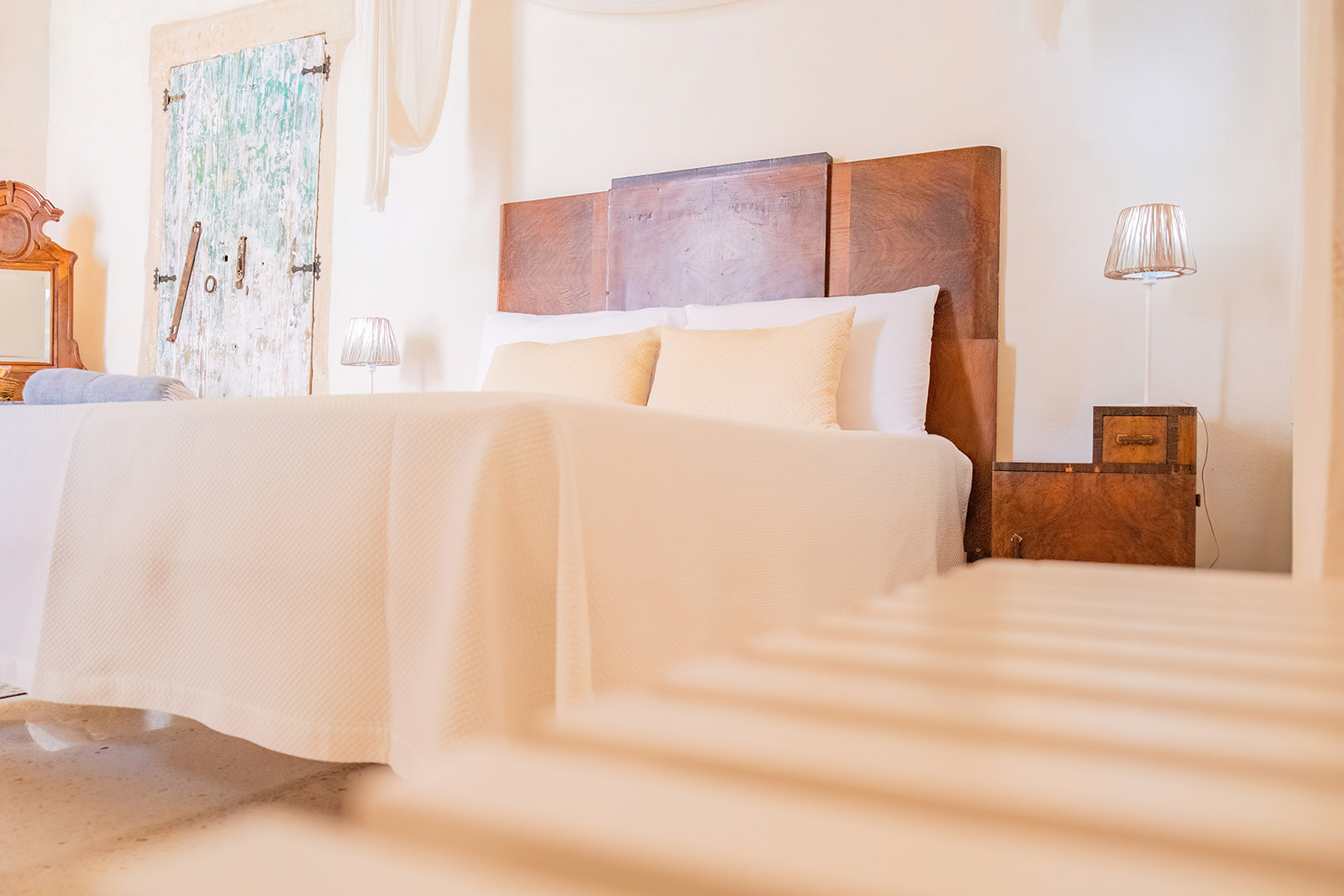 Letto matrimoniale con testata in legno massello, cuscini gialli e lampade in tessuto