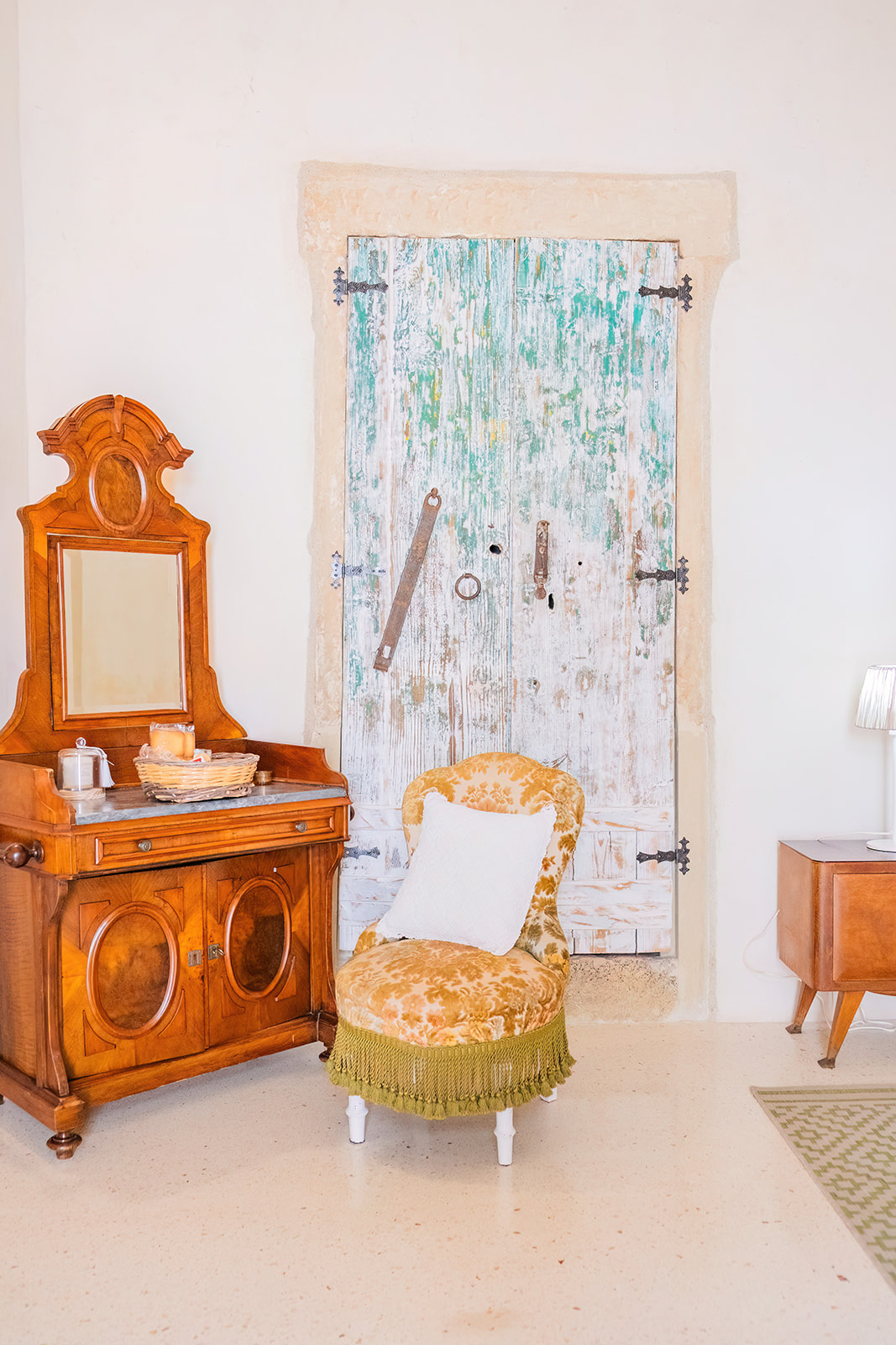 Cassettone antico in noce con poltroncina in damasco oro davanti alla porta verde