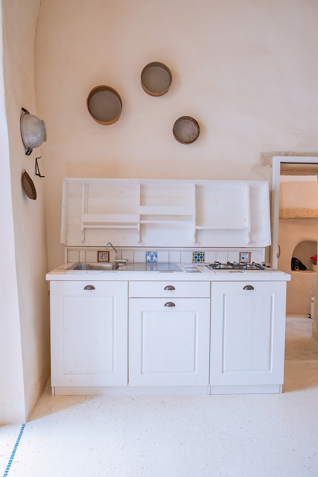 Cucinino bianco della Dimora 1 con setacci in legno appesi alla parete