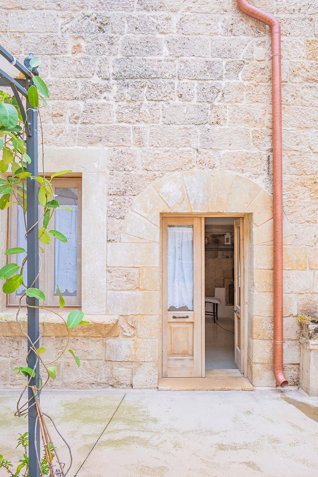 Ingresso ad arco in pietra leccese di una delle dimore con vegetazione rampicante