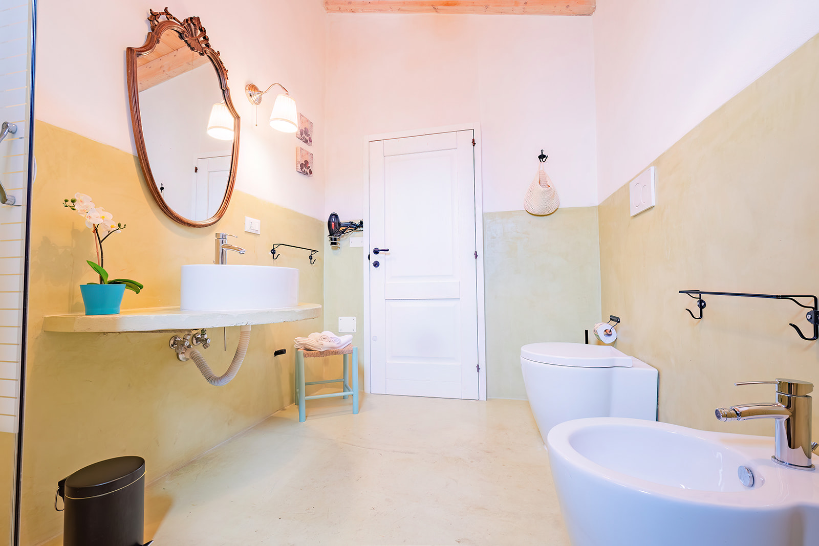 Bagno della Dimora 3 con parete bicolore bianco e giallo pallido e specchio antico in legno