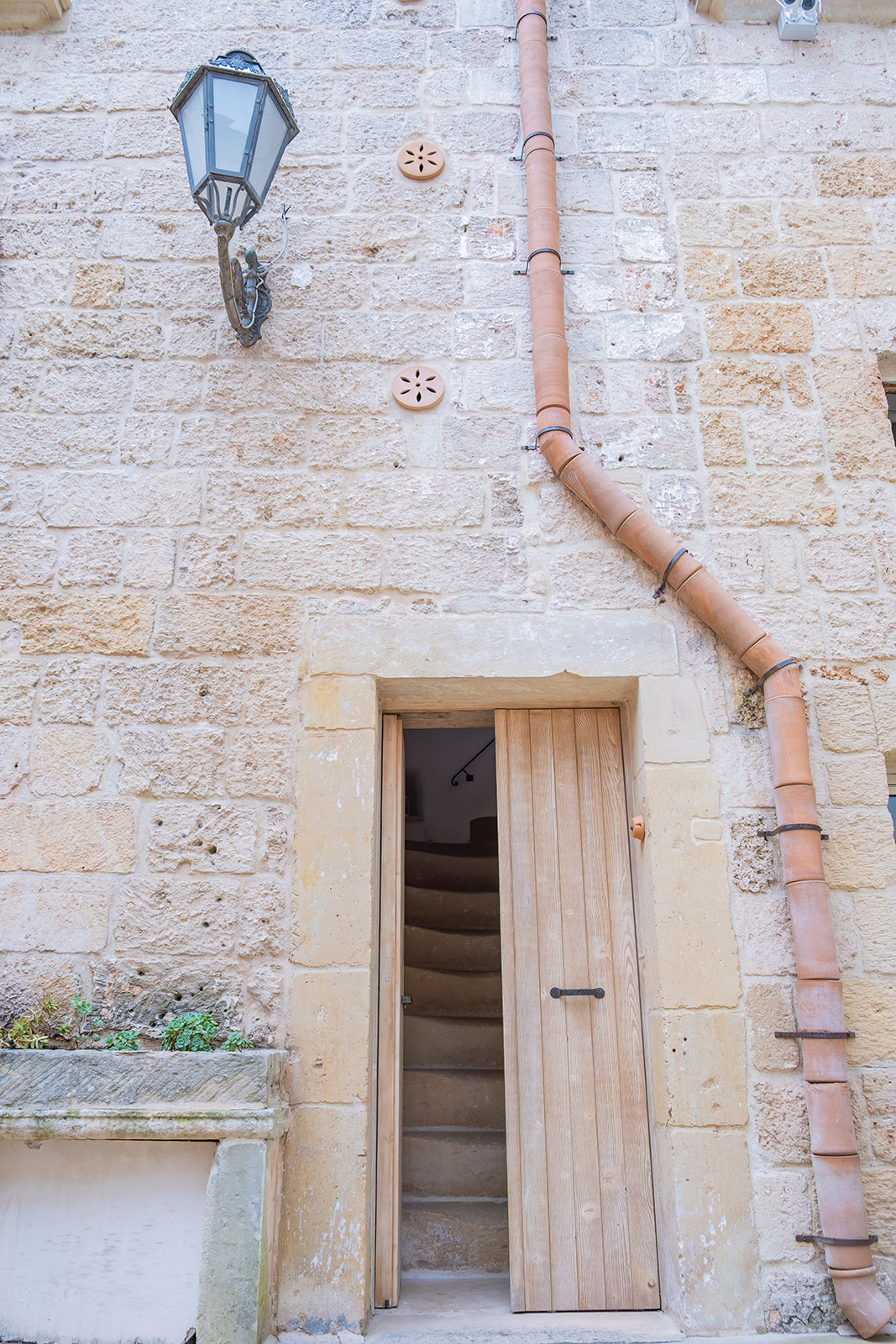 Ingresso esterno della Dimora 3 con porta in legno chiaro e scala in pietra che sale al piano superiore
